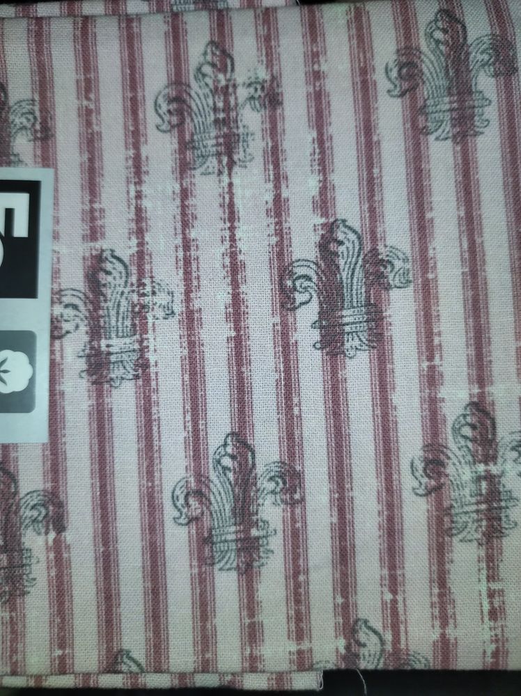 a swatch of light pink fabric with vertical stripes in dark red, and grey fleur de lis designs scattered over