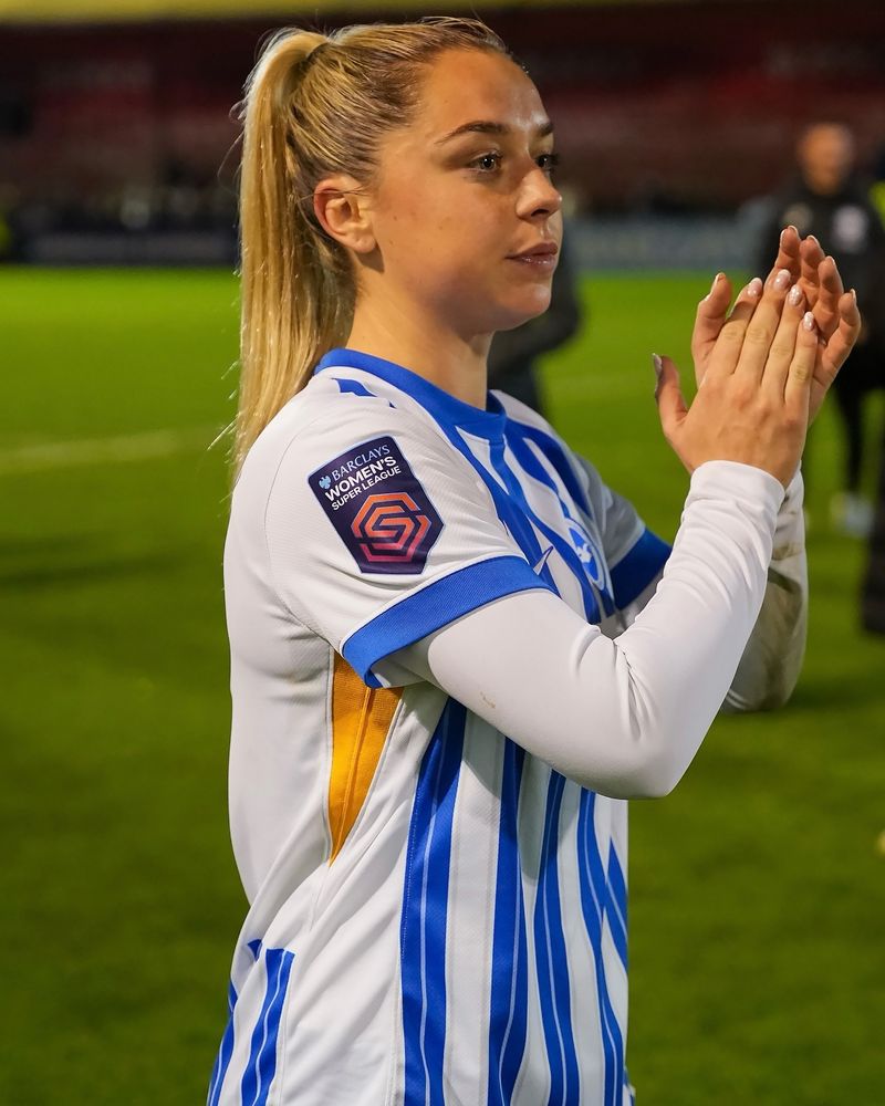 Poppy Pattinson claps fans at full time in BHAFC home kit. 