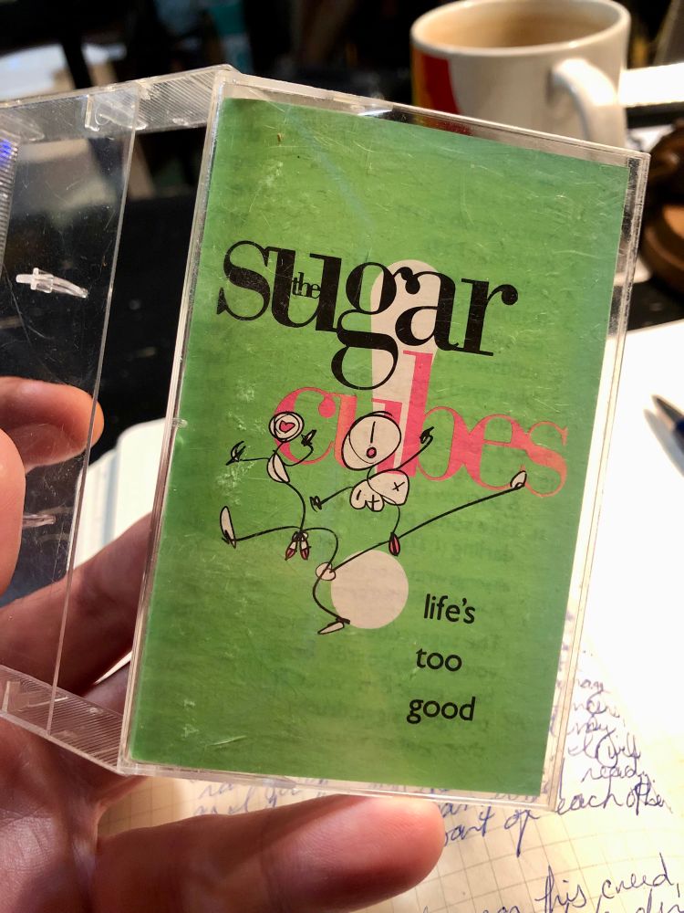 Cassette tape case: The Sugar Cubes ~ Life's Too Good (1988), it's light green with two groovy-dancing, anatomically hilarious stick figures: one appears to have three tits, a lil pink volvo and an exclamation mark for a face, and the other has two dinks & balls and a love-heart for a face.