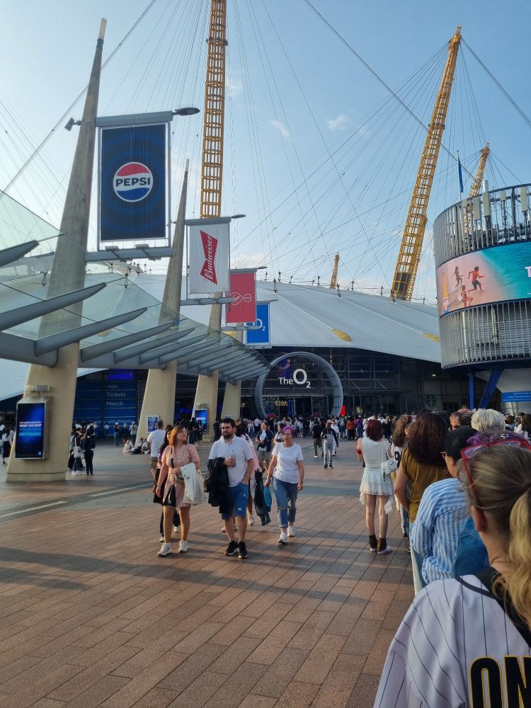 ARMY queueing outside the O2 arena for day one of Run:Seokjin ep. Tour in London. The venue entrance with the O2 logo  is visible in the background. 