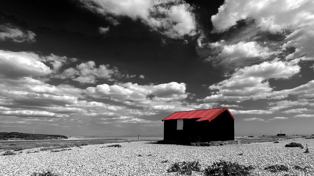 Black and white photograph of a black building in coastal location