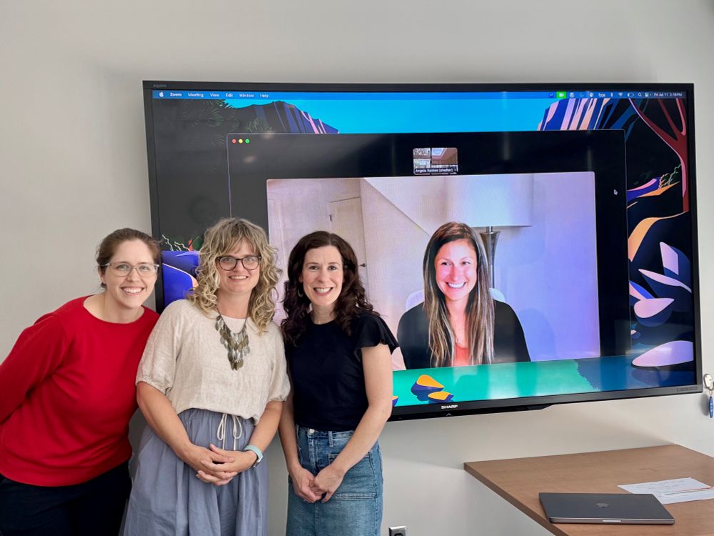 Angela Santee appears in a red sweater next to her three committee members, with one appearing on a large screen via Zoom. 