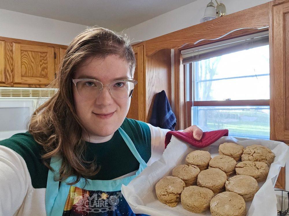 Claire shows off a tray of freshly baked biscuits in xyr kitchen.
