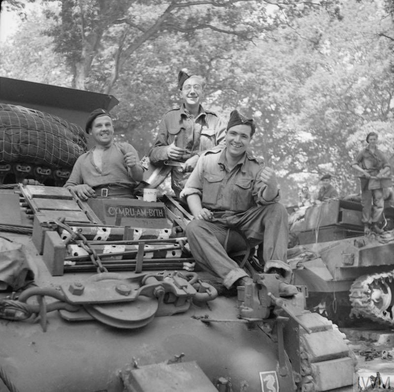 Tank crew sat on their recovery vehicle.