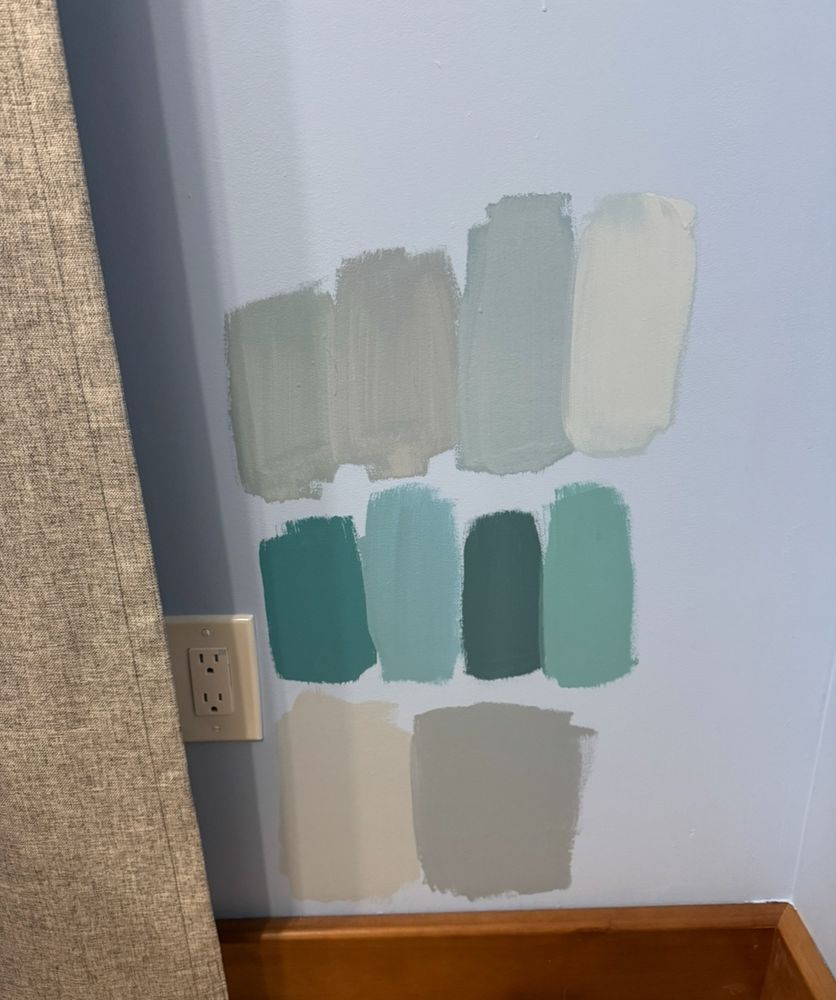 A blue wall with ten different shades of blue/grey painted in test patches 