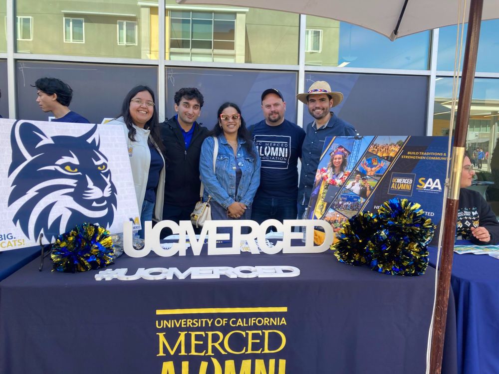 Two alumni pose with three UCMAA Board members as they table during Bobcat Day. 