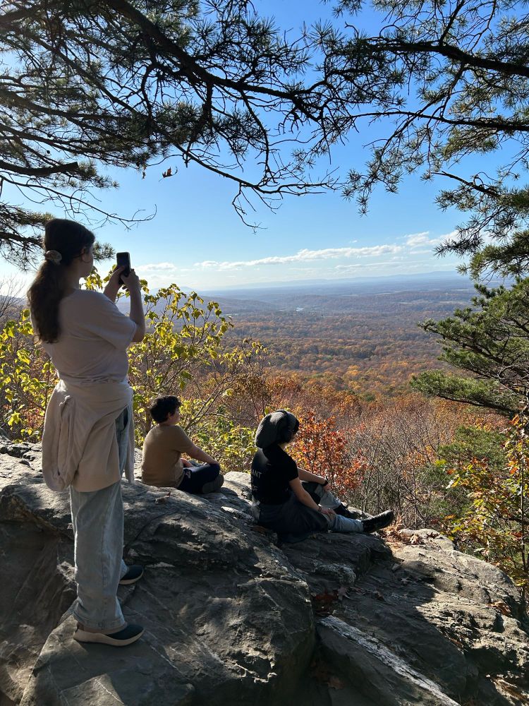 Three older kids on an overlook of beautiful Fall trees.