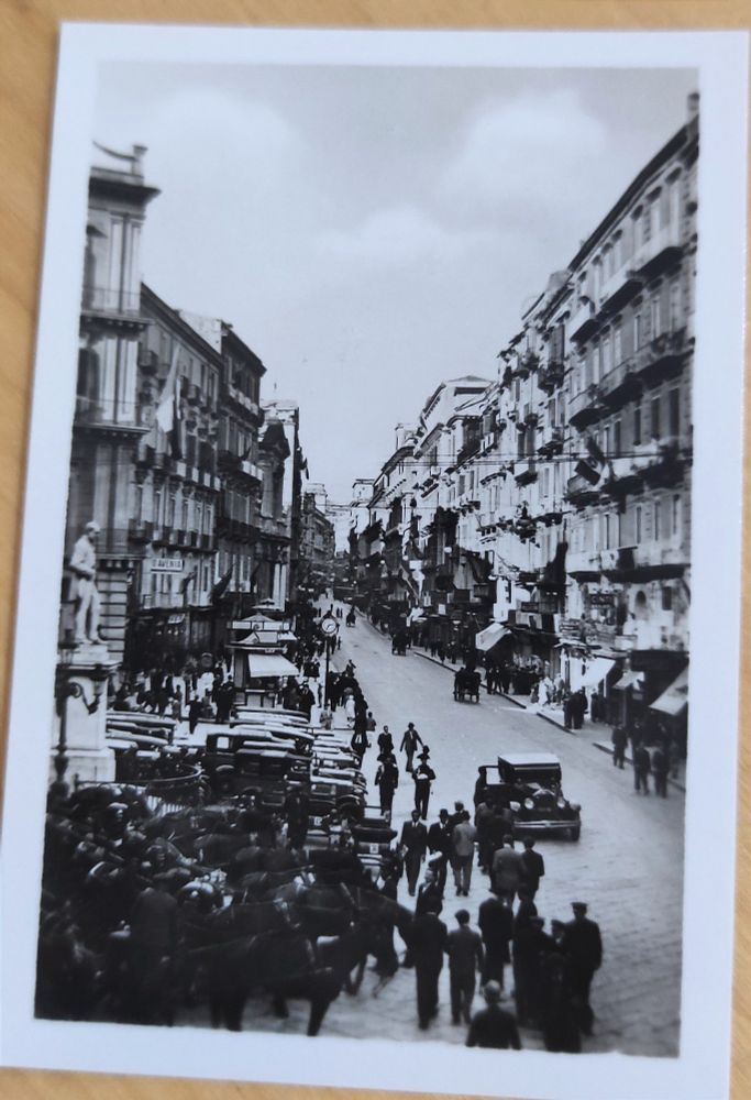 street with just one car and many cars and horses waiting while many people walk