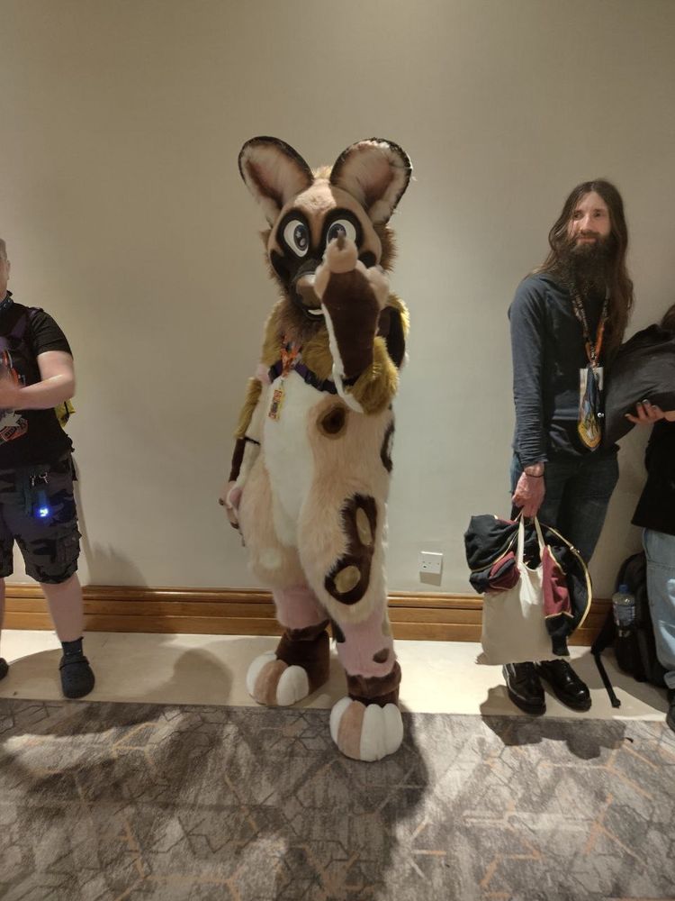 A fursuit of Asha, an African Wild Dog, failing to give the middle finger