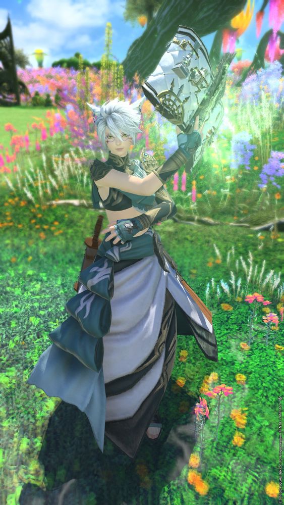 A final fantasy 14 screenshot of a white-haired, bespectacled Miqo'te holding up a glowing book with green fairy wings. The background shows a meadow of colorful wild flowers.
