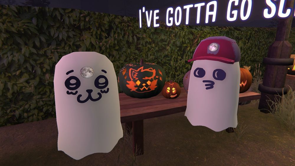 Two ghost next to their pumpkin carvings.