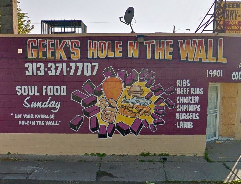 The painted brick building sign of Geek’s Hole In The Wall restaurant.