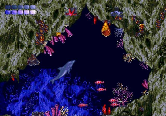screenshot from the Ecco the Dolphin game.  A dolphin swims in a dark underwater cavern full of corals and small fish.