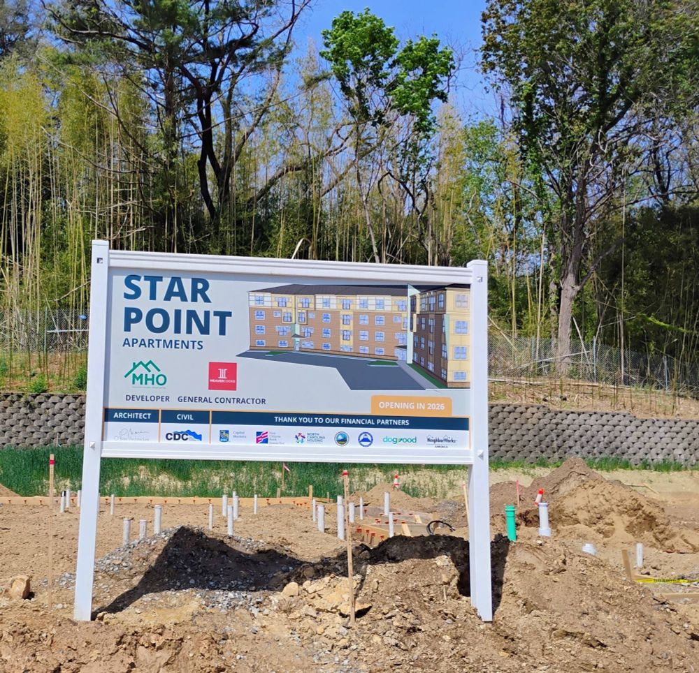 Sign on the project construction ground that reads "Star Point Apartments" with a computer-generated image of the apartments, logos for different funders and developers, and further information on the project.