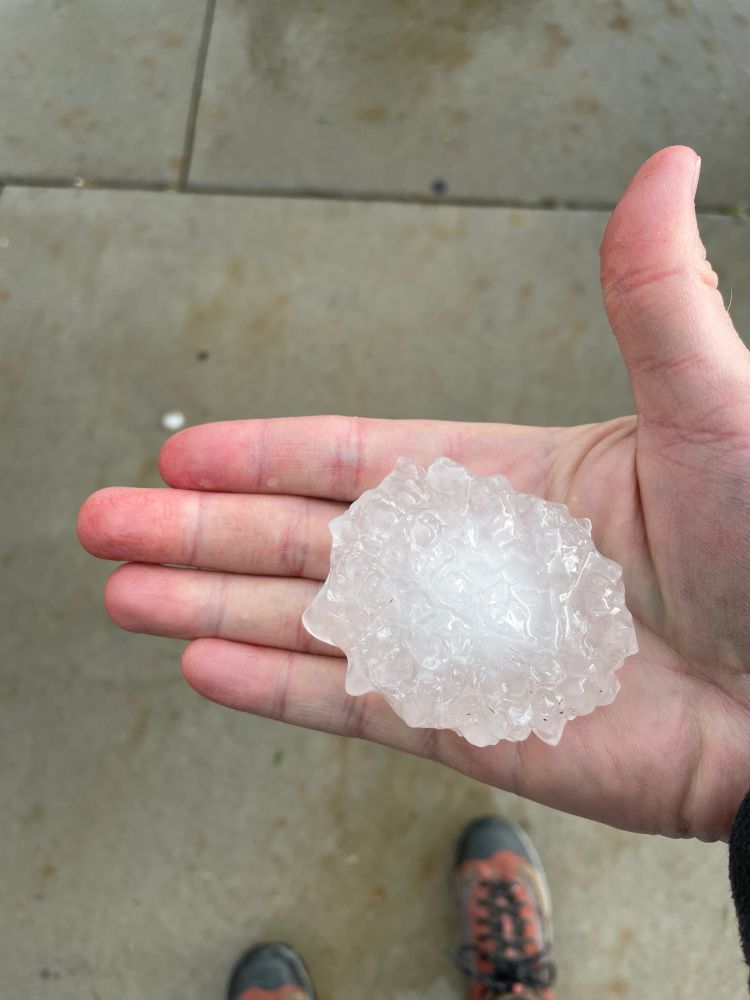 Man holding a large hailstone. Between golf ball and baseball sized 