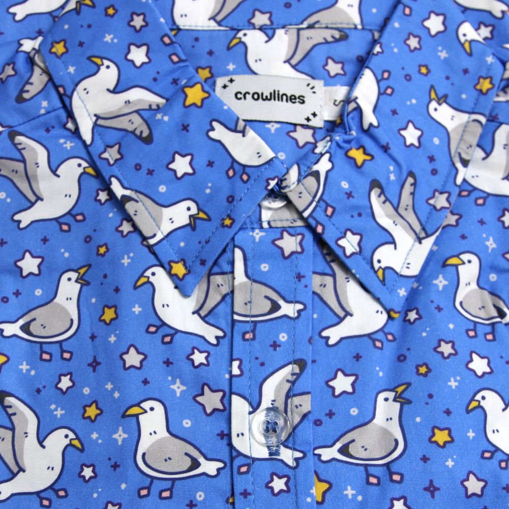 blue button up shirt patterned with seagulls and silver and gold stars