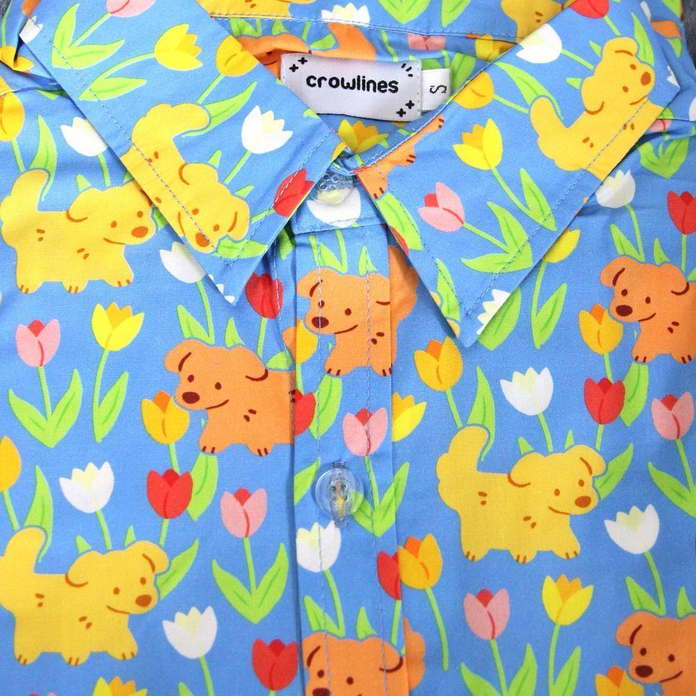 blue button up shirt patterned with dogs and tulips drawn in a cute style