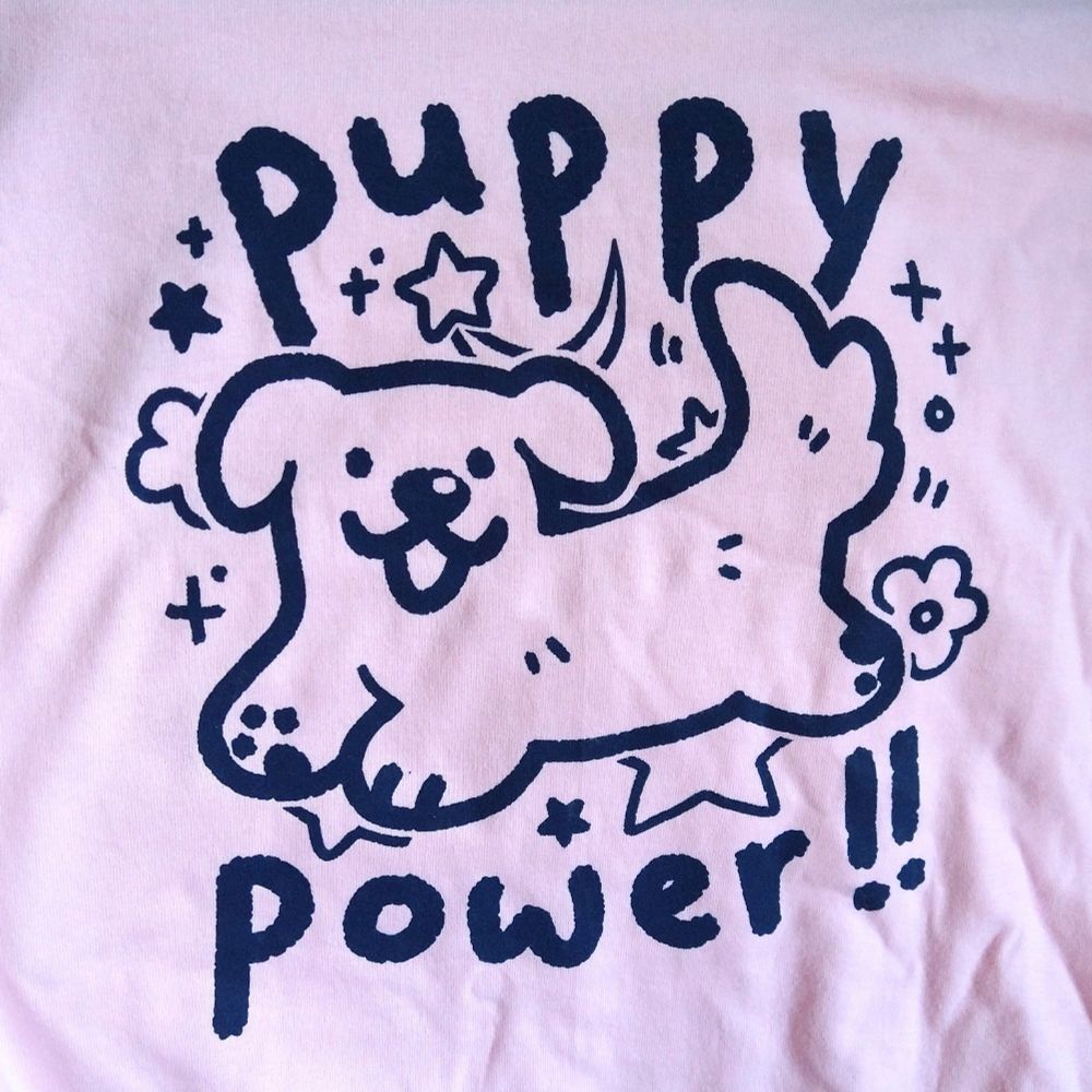 pink shirt printed with drawing of a happy dog with text "puppy power!!"