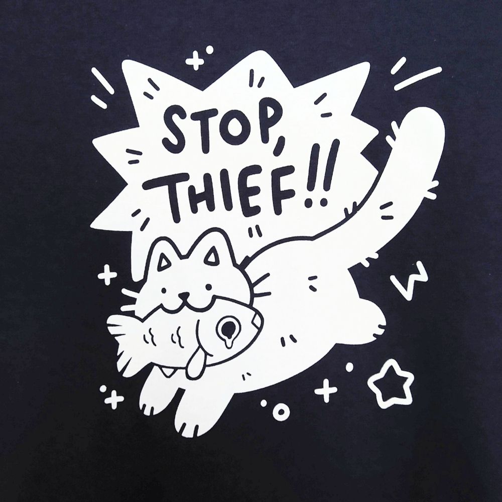 navy blue tee printed with white ink graphic of cat running with fish in its mouth, drawn in a cute style. dynamic speech bubble behind cat reads "STOP, THIEF!!"