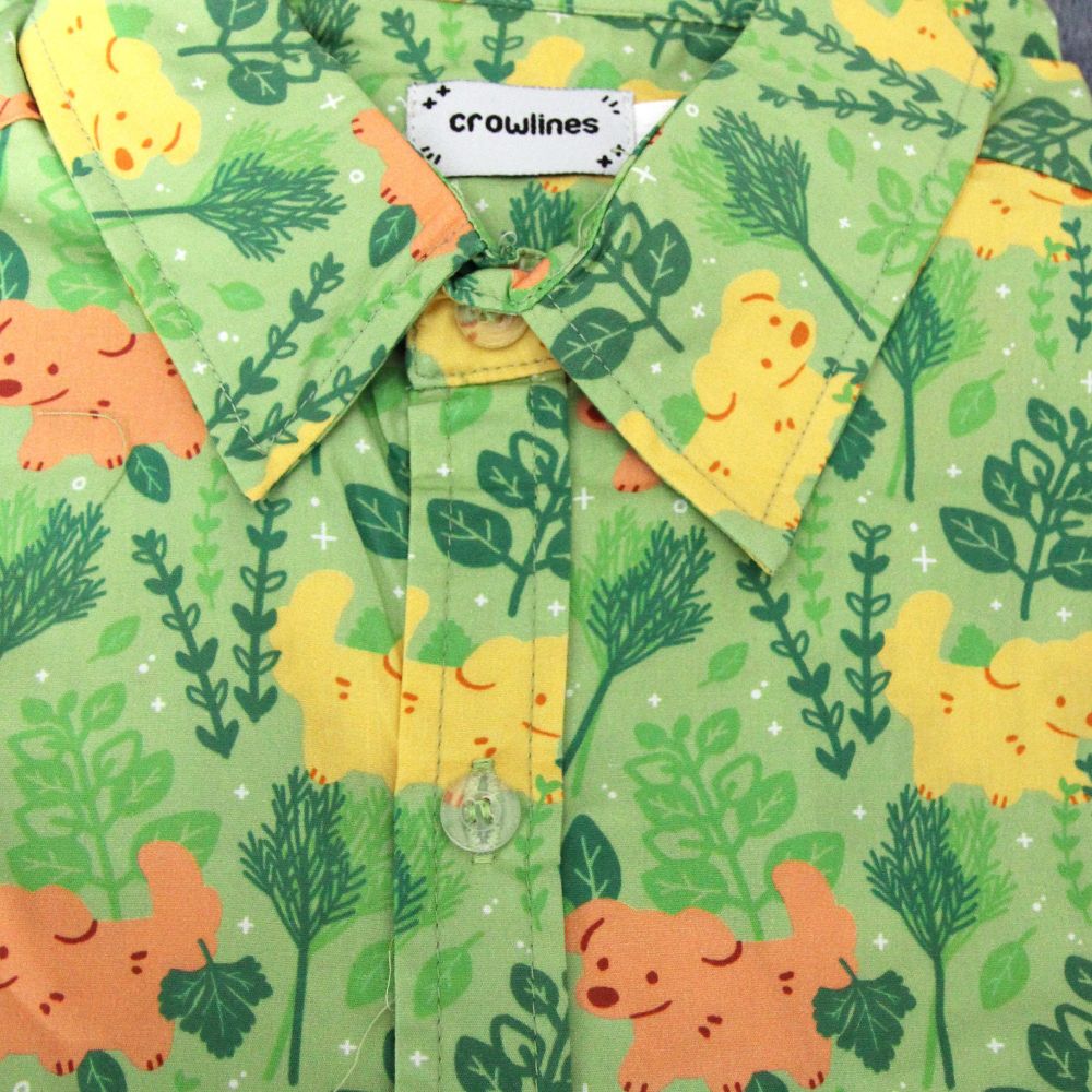 green button up shirt patterned with dogs and herbs