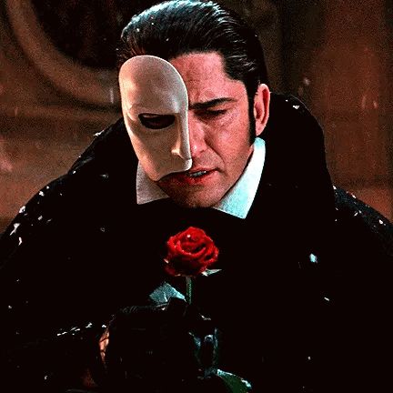 a man with a mask on his face is holding a rose .