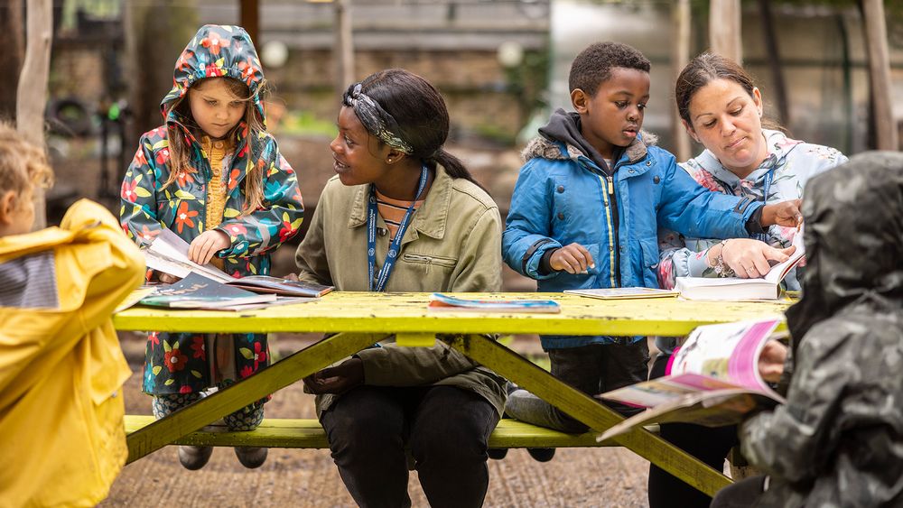 Two children and two educators sit at a table doing crafts. Mat Wright for UCL.
