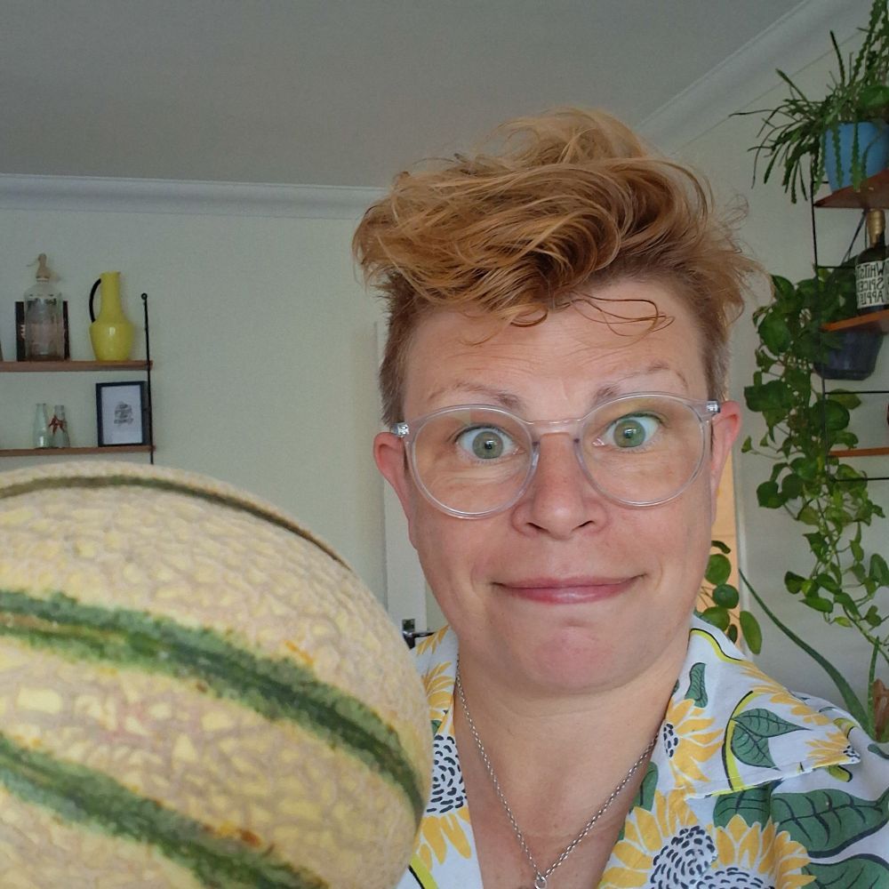 Me wearing a shirt with sunflowers on and holding a striped melon