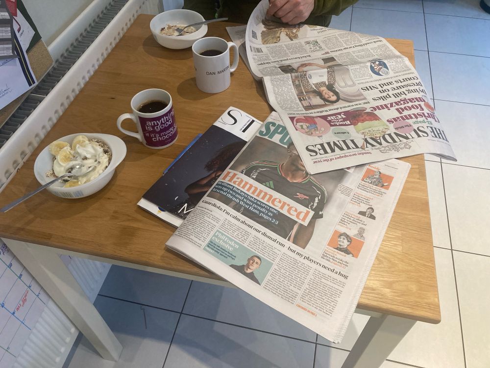 Muesli in a bowl, coffee in mugs and the Sunday Times spread out on the wooden top of kitchen table.
