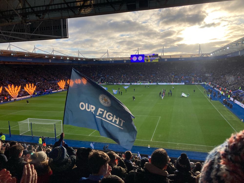View of the King Power pitch ahead of Leicester City v Manchester City. A blue flag which reads Our Fight is held high above the fans. Flames coming out of those machine thingies at the side of the pitch too!