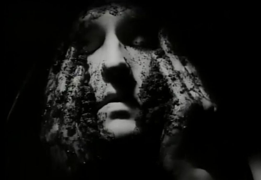 Black & White image of person rubbing dirt on their face