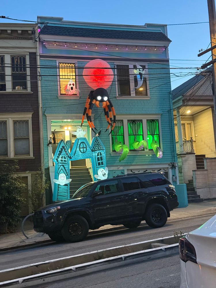 a Victorian house with Halloween decor: a spider, ghosts, spooky lights 