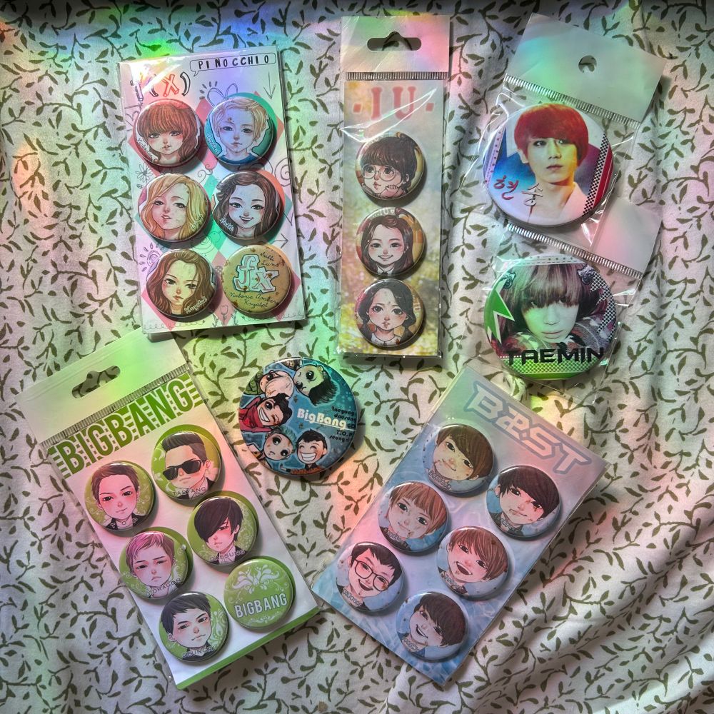 24 button "badges" featuring the faces of K-pop stars from the early 2010's such as Big Bang, f(x), B2ST, IU, and Taemin from SHINee.