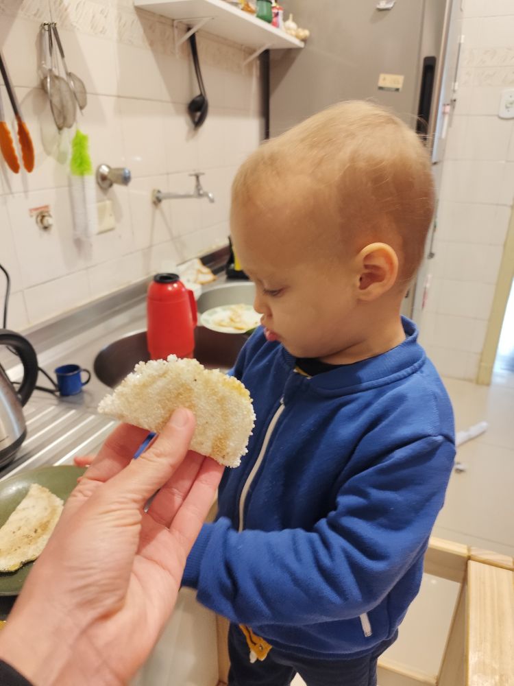 Bebê grande ao lado de uma mini tapioca com recheio de banana para comparação 