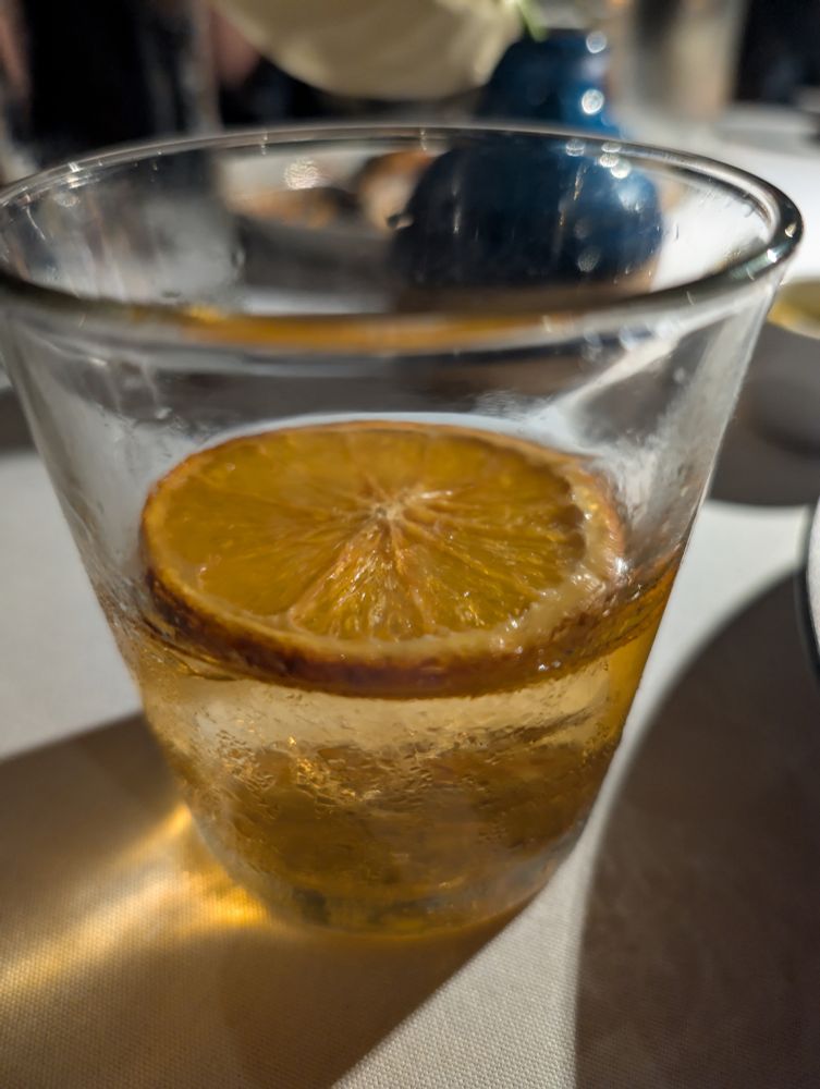 Reposted so I remembered to add this alt text. This is the Dad Joke, a cocktail in a short tumbler glass, containing Four Roses Bourbon, Updog, Montenegro Amaro, John D Taylor's Velvet Falernum, Orange Bitters and a dried orange slice on top.