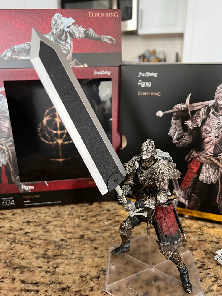 This is a picture of the Figma Raging Wolf action figure from Elden Ring. It depicts one of the more popular armors from the game, and he’s holding a giant greatsword. In fact, it’s the greatsword the character Guts uses from the manga Berserk. I actually bought the sword separately off eBay just so I could take a picture of this figure holding it, because the sword is in the game Elden Ring mostly as an Easter egg due to how influential Berserk is to FromSoft’s games. I’ve actually never read the manga but I think the sword looks cool. Anyway, yeah, it’s a picture of a toy holding a sword. 