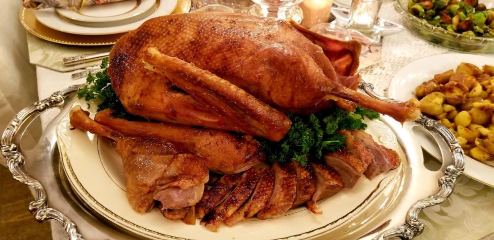 a roasted goose on a platter with a drumstick and slices of breast meat