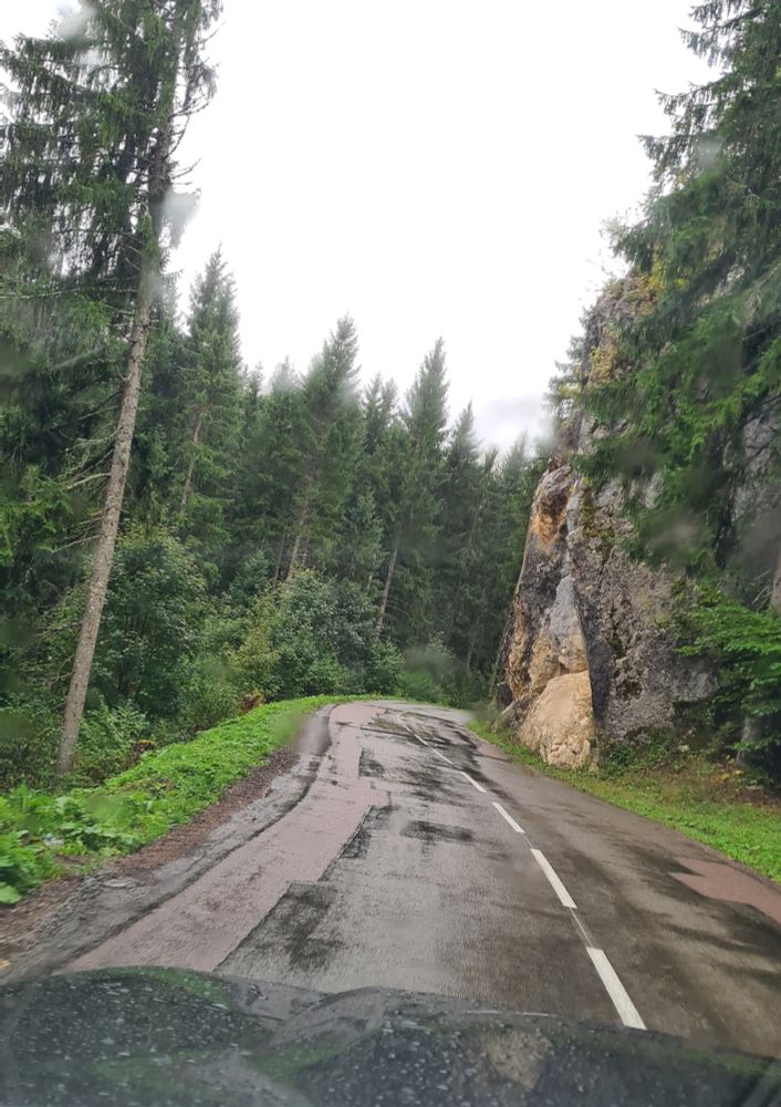 Photo d'une route mouillée dans une forêt dans le Jura avec une belle falaise affleurante.