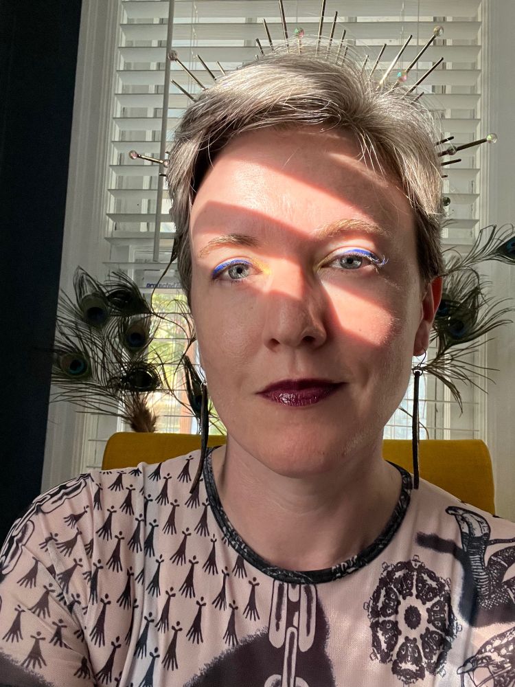 Jackie as Reina Valencia poses close-up with blue eyeliner and a radiating crown.