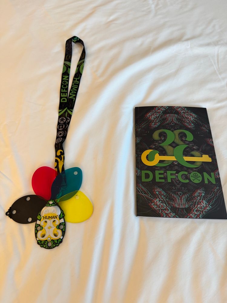 Defcon 33 badge and accompanying book. Badge features multiple colored leaves that are exposed to be able to look for hidden items in art around the conference