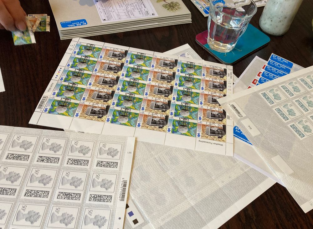 A table full of postage stamps and envelopes being assembled.