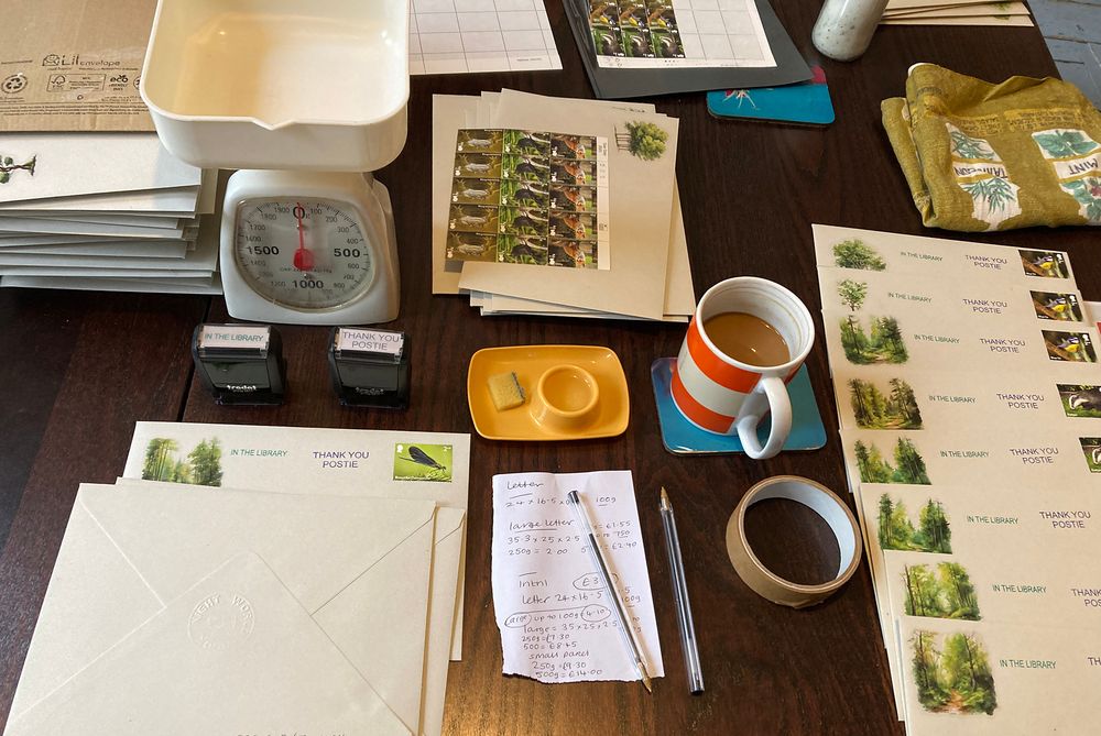 A table full of envelopes and postage stamps being assembled.