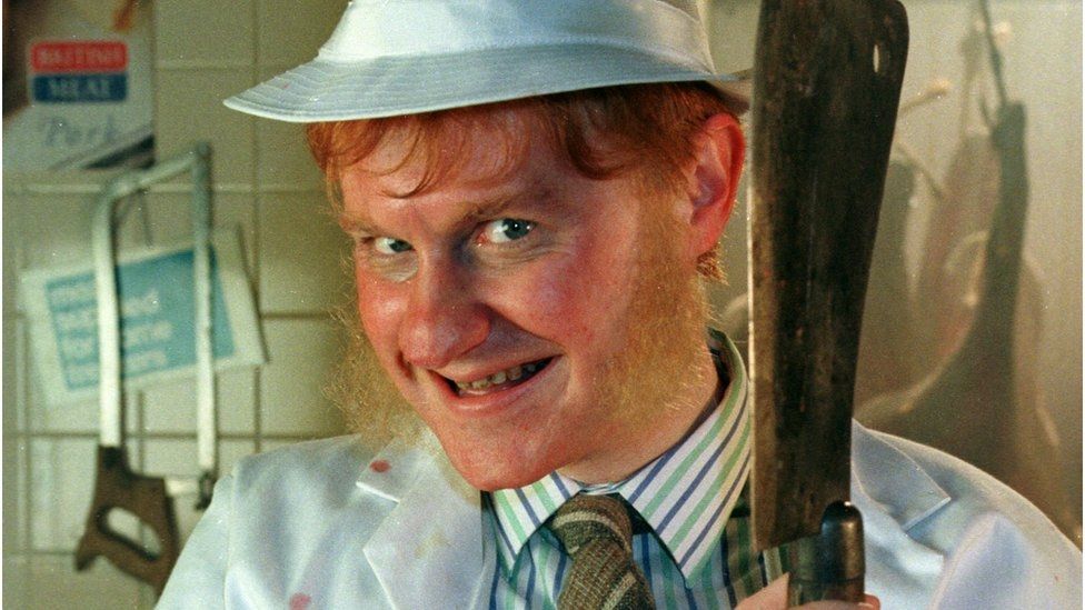 Picture of Hillary Briss from the League of Gentlemen holding a cleaver and grinning. 