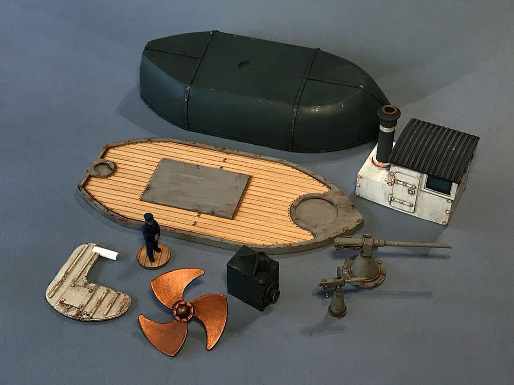 Showing the parts of the neff kit. Top to bottom. Lower hull, wheel house, deck with veneer, deck gun, rudder, engine block, prop and maxim. 