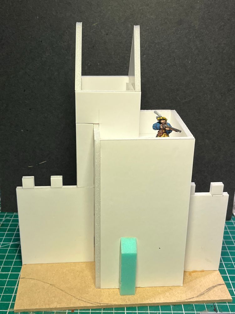 A front view of the town wall. Cobbled together from 5mm foamcore. There is a tower in the middle and a wall coming out of each side. A GW plastic Empire handgunner is stood on the tower looking out for unruly orcs (is there any other kind).
