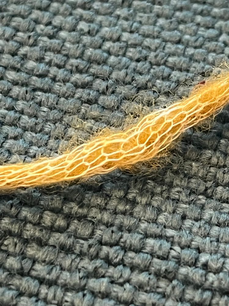 Close up of golden yellow yarn with small interlocking threads resembling the shedded scales of snake skin. 