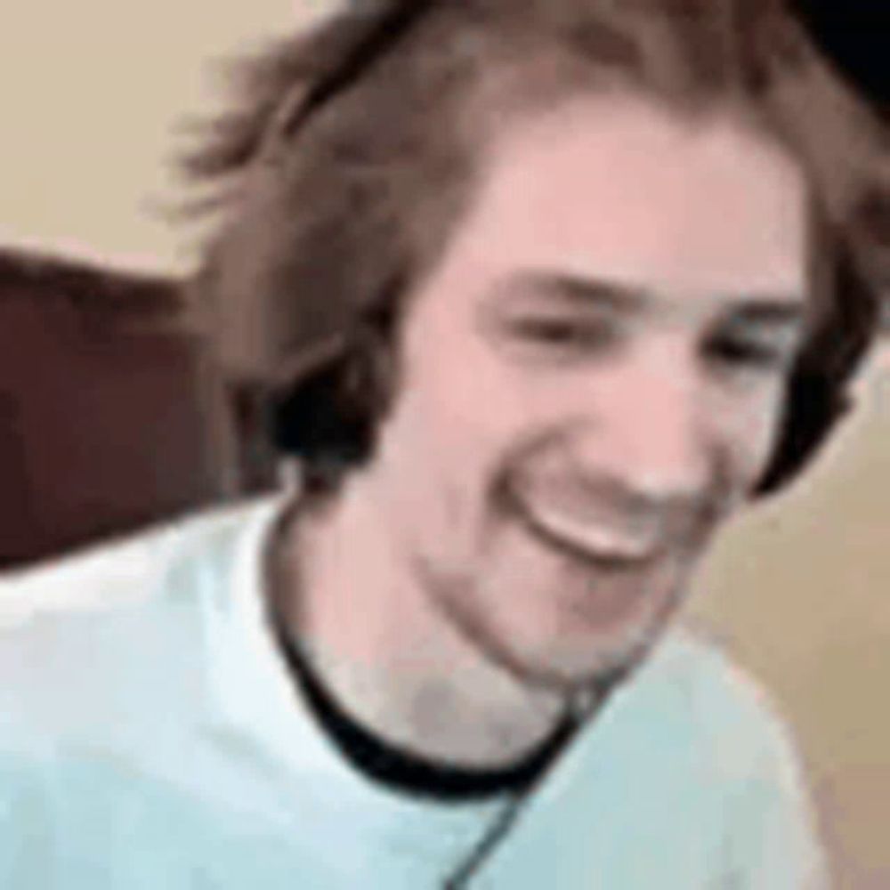 a man wearing headphones and a white shirt is smiling while sitting in a chair .