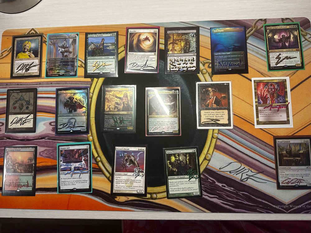 A number of signed cards on a Mox Jet playmat.