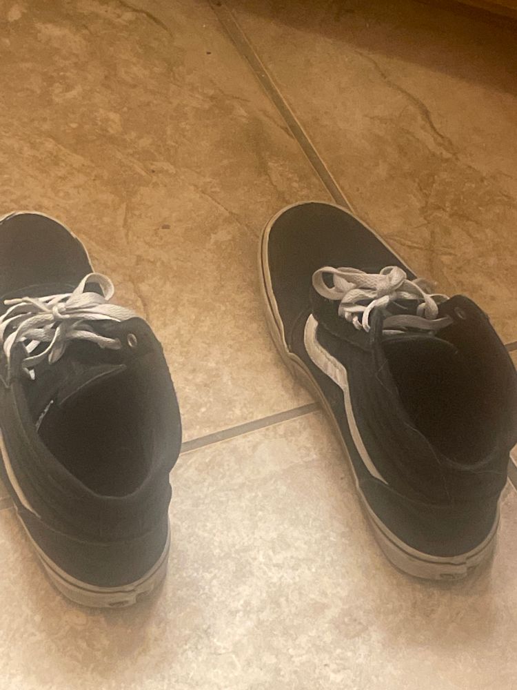 A pair of vans shoes on a tile floor.