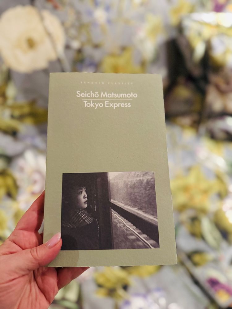 Photograph of a book: ‘Tokyo Express’ by Seichō Matsumoto, translated by Jesse Kirkwood and published by Penguin Books. 

This Penguin Classics paperback is in their tradition pale sage green, with the imprint, authors name and book title in a simple white font. Below is a black and white photograph of a young Japanese woman, seated in a train carriage and looking out of the window, the train tacks are visible through the distorted glass. 
On the cover leaf, it says that the photograph was taken by Werner Bischof, a Swiss photo journalist. 