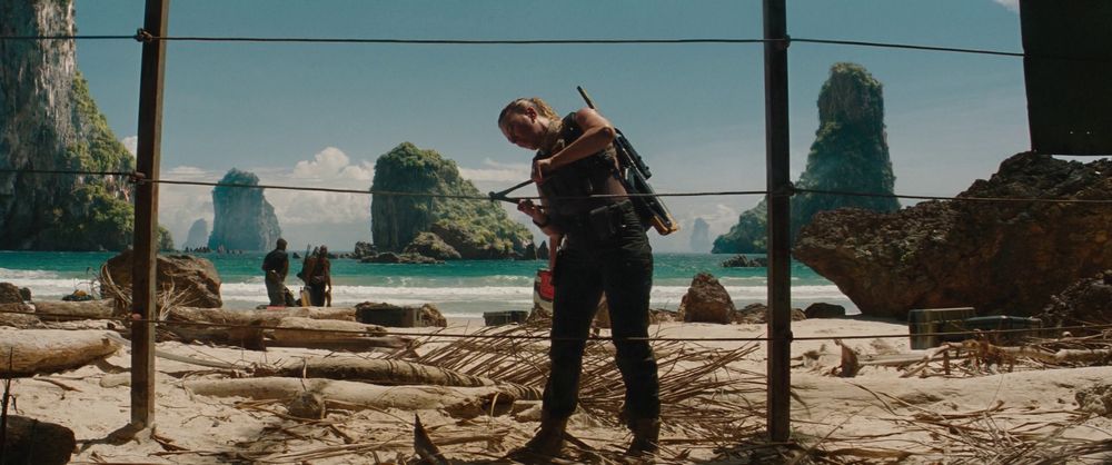 Scarlett Johansson schneidet das mittlere von drei Stahlseilen eines Zaunes kaputt, obwohl man zwischen den Seilen leicht durchschlüpfen könnte.